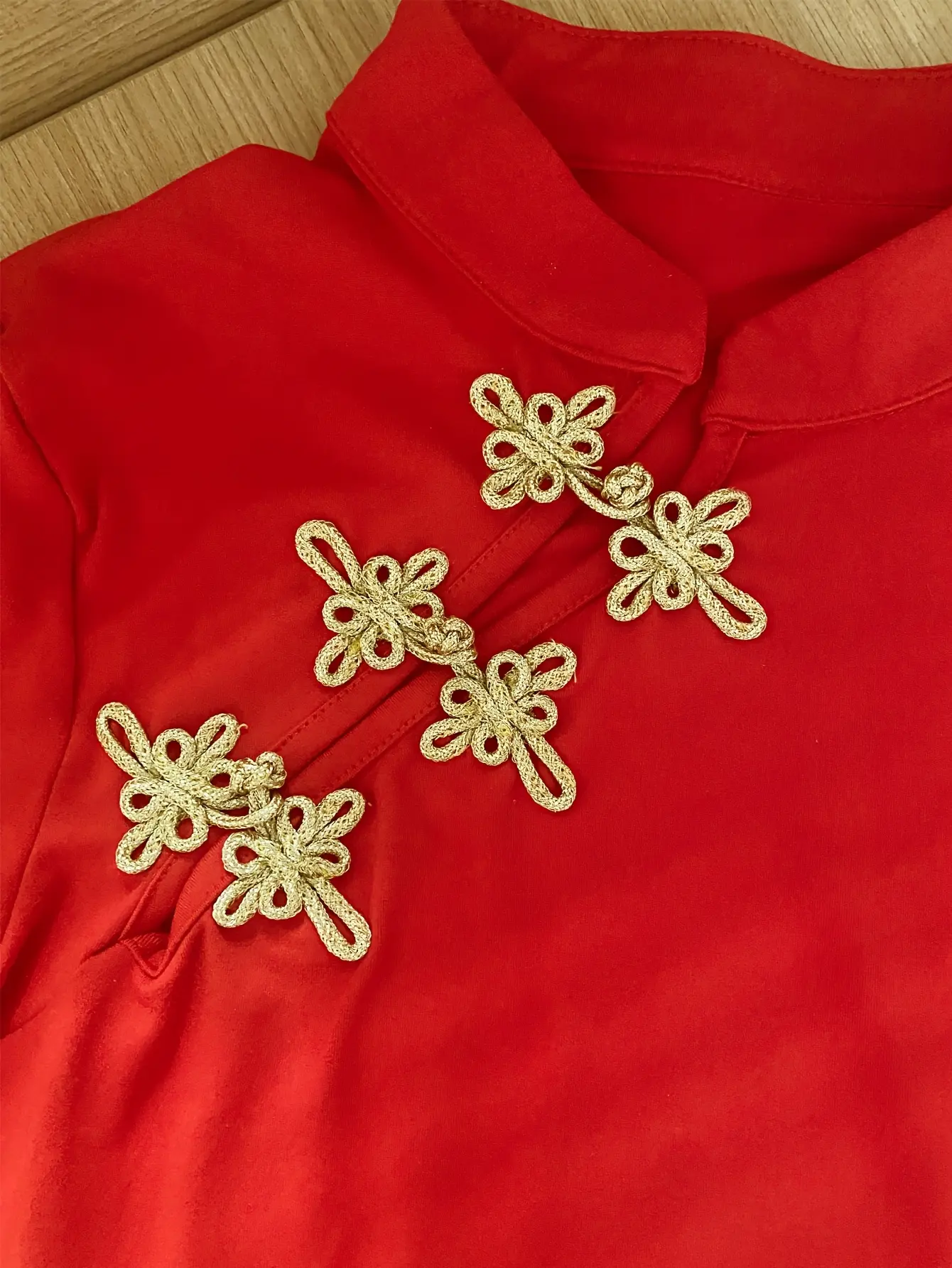 Women’s red mandarin-collar top gold frog closure detail