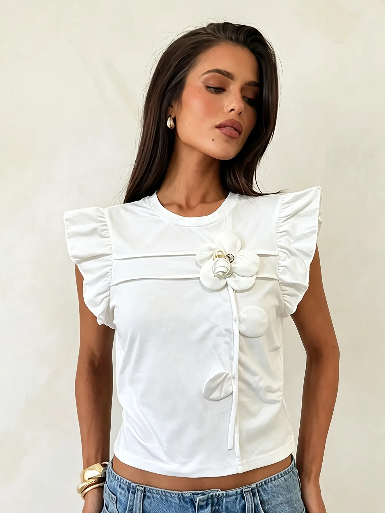 Model wearing white ruffle-sleeve floral applique top