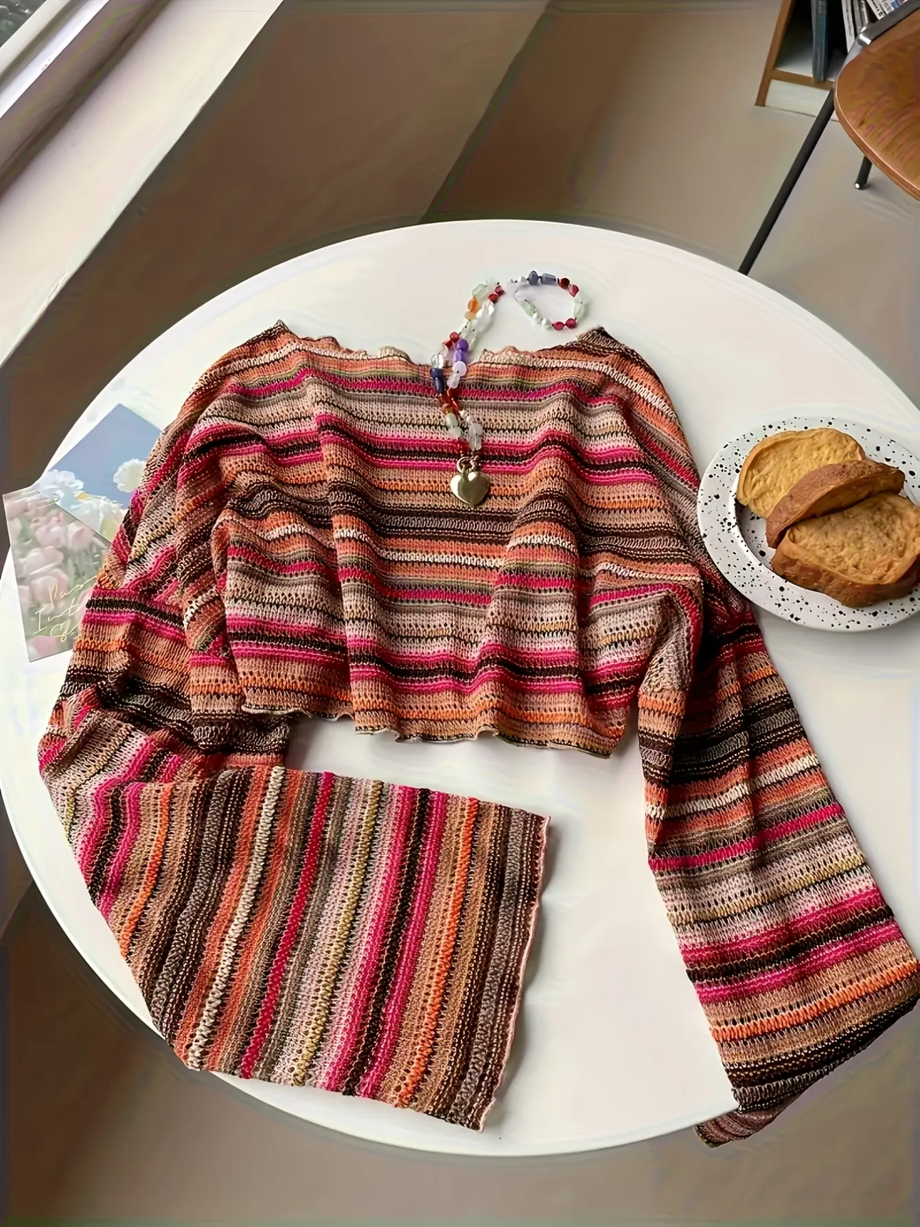 Multicolored striped crochet-knit bell-sleeve top laid flat