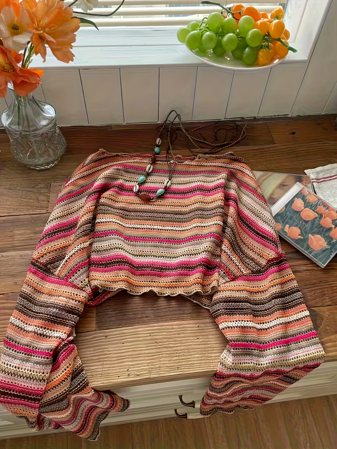 Multicolored striped crochet-knit bell-sleeve top laid flat