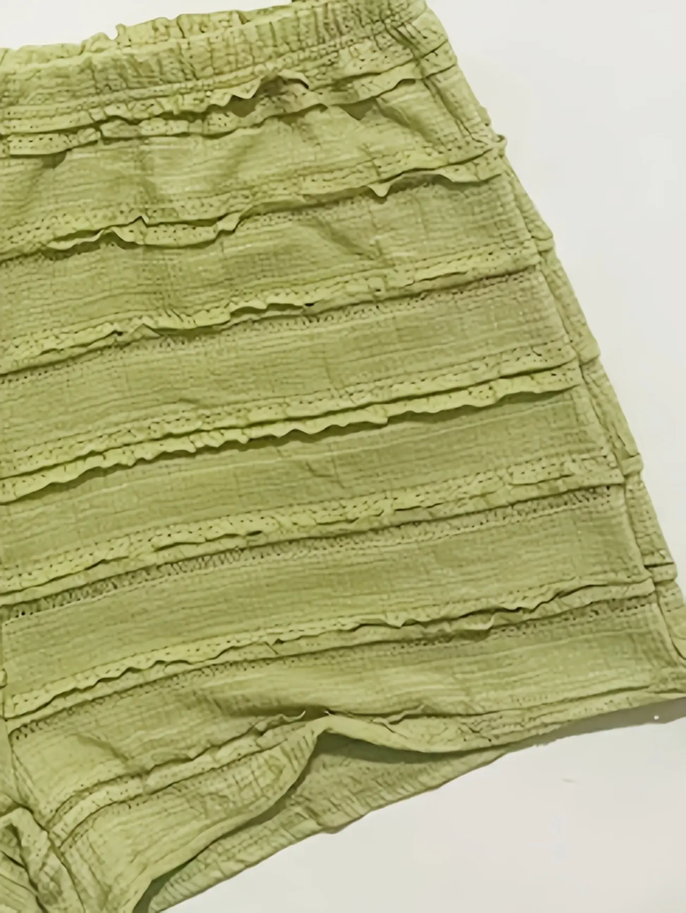 Close-up of green knit shorts with textured tiers